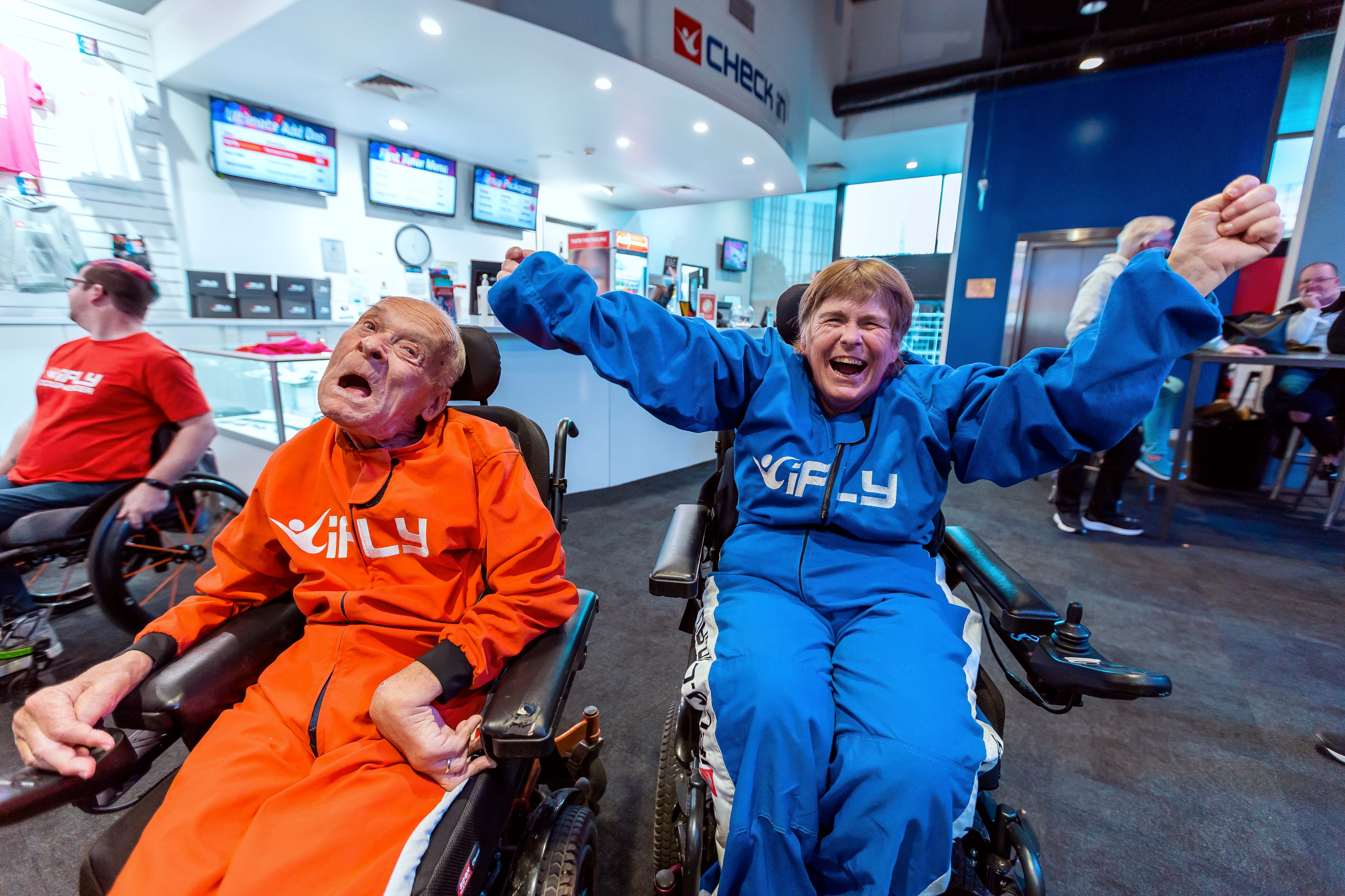 Two smiling flyers in flight suits at iFLY
