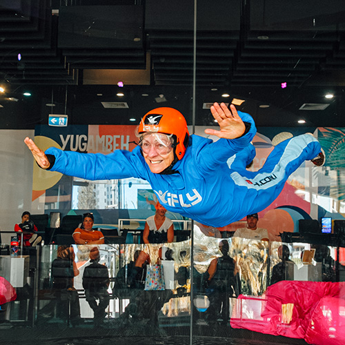 A flyer in a blue suit and orange helmet floating above the tunnel floor