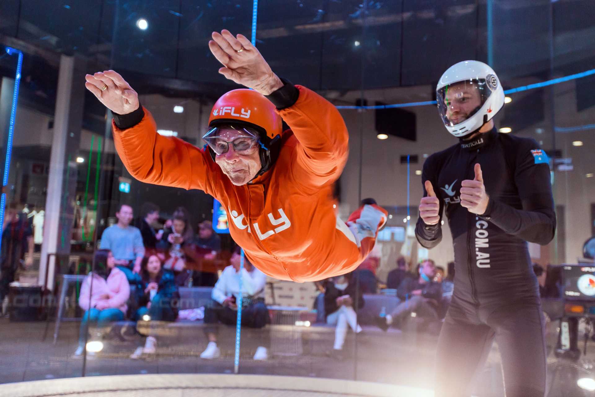 Grandmother in orange jumpsuit flying with instructor in black jumpsuit.