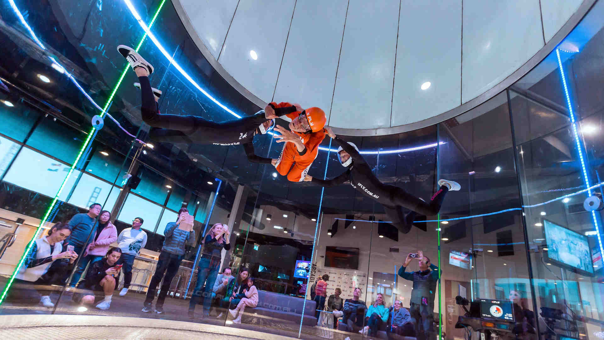 Two instructors assisting a person living with disability whilst indoor skydiving