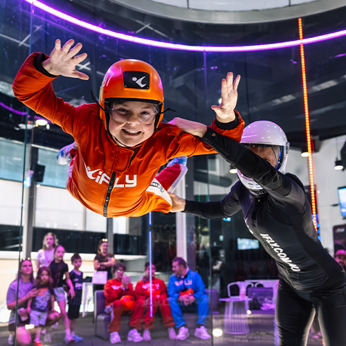 Flyer in an orange flight suit supported by an instructor