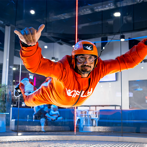 Flyer in an orange flight suit in the wind tunnel